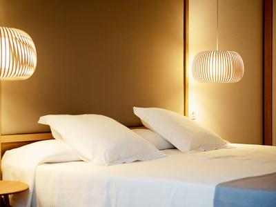 Elegant hotel room with two beds, white pillows, and soft lighting.