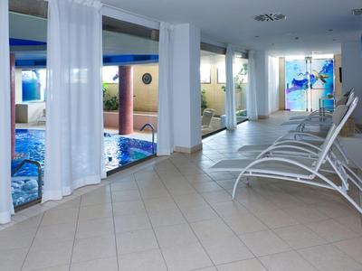 Indoor pool area with white lounge chairs and sheer curtains