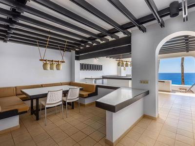 Salon moderne avec banquette et vue sur la mer à travers une arche.