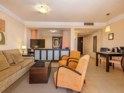 Espace salon d'hôtel confortable avec canapé, fauteuils et table à manger aux tons neutres.