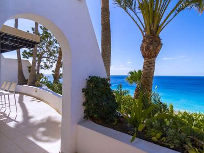 Balcon avec des arches blanches, des palmiers et une vue sur la mer bleue et le ciel.