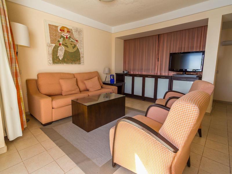 Pohodlný obývací pokoj se dvěma pohovkami, konferenčním stolkem a TV v hotelovém pokoji.