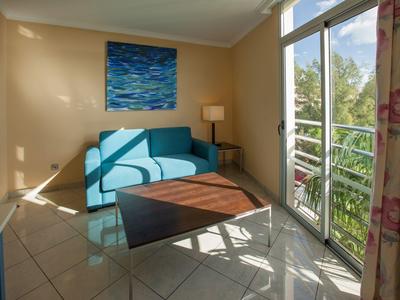 Cozy corner with blue sofa, wooden table, and balcony with green view.