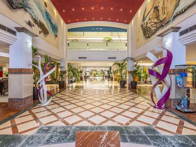 Großer, heller Hotellobby-Eingangsbereich mit farbenfrohen Skulpturen und dekorativen Wandgemälden