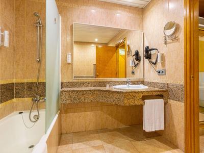 Elegantes Badezimmer mit Badewanne, Waschbecken, Spiegel und einem Handtuch an der Wand.