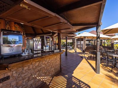 Outdoor-Bereich einer Bar mit Getränkeservice und Sitzbereichen unter Sonnenschirmen.