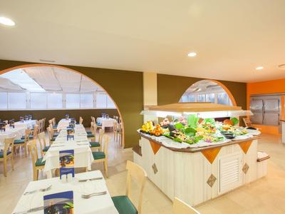 Restaurante luminoso con área de buffet y mesas preparadas en un hotel.