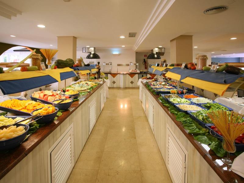 Buffet with a variety of dishes and salads in a bright room.