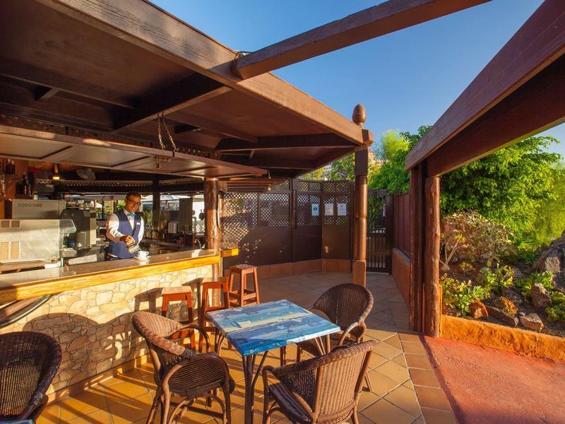 Open terrace with tables, chairs, and bar area overlooking outdoor natural scenery.