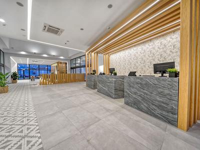 Nowoczesna lobby hotelowa z szarą marmurową recepcją i drewnianym wystrojem.