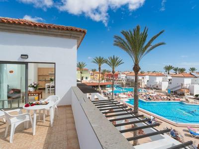 Balkon z widokiem na basen i białe budynki pod niebieskim niebem