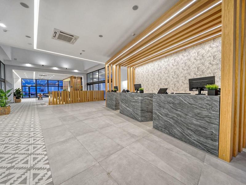 Moderne Empfangshalle mit grauem Marmor-Desk, Holzvertäfelung und großem Lichtraum.