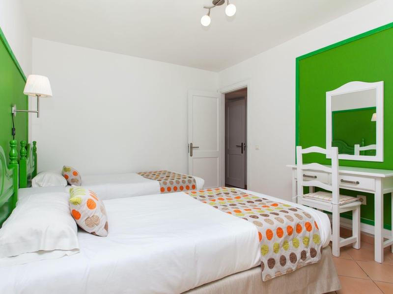 Lichte hotelkamer met twee eenpersoonsbedden, groene accentmuur en een klein kaptafeltje.