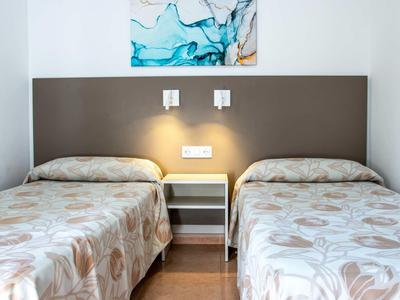 Een hotelkamer met twee eenpersoonsbedden, een nachtkastje en moderne kunst aan de muur.