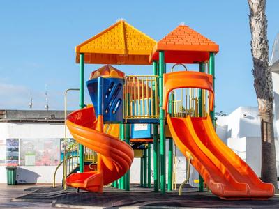 Colorful children's playground with slides and climbing frame under a blue sky.