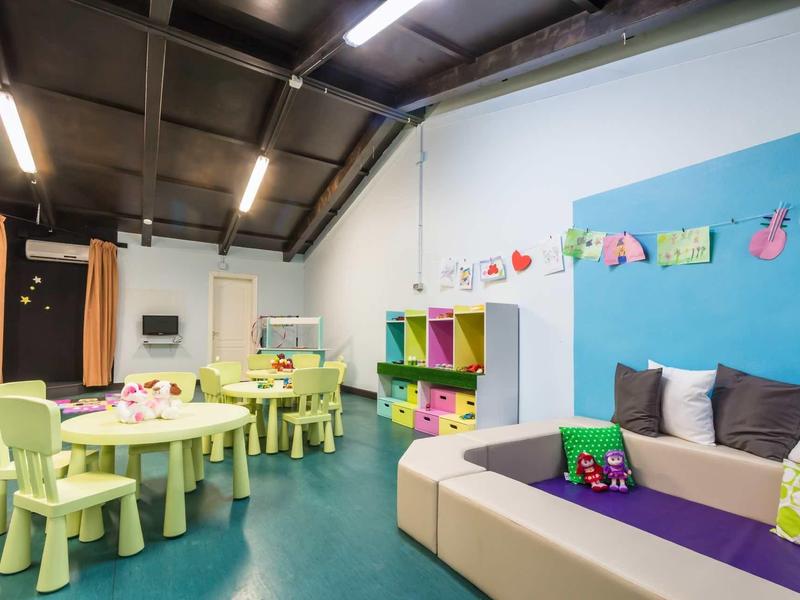 Colorful children's area with tables, chairs, and toys in a bright room.