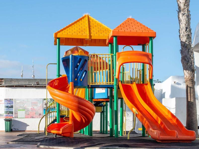 Colorful children's playground with slides and climbing frame under a blue sky.