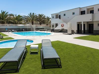 Area piscina moderna in hotel con lettini, prato e palme.