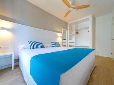 Modernes Hotelzimmer mit Doppelbett, blauen Akzenten und offenem Kleiderschrank.
