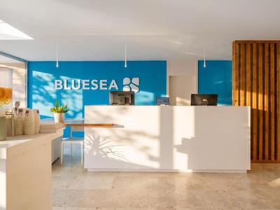 Helle Lobby eines Hotels mit weißem Empfangstresen und blauem Hintergrund.