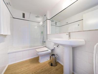 Weiß gefliestes Badezimmer mit Badewanne, Wand-WC und großem Spiegel über einem Waschbecken.