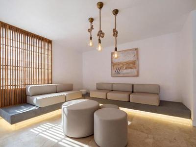 Modernes Hotelzimmer mit grauen Sofas, Hockern und Holzlamellen an der Wand.
