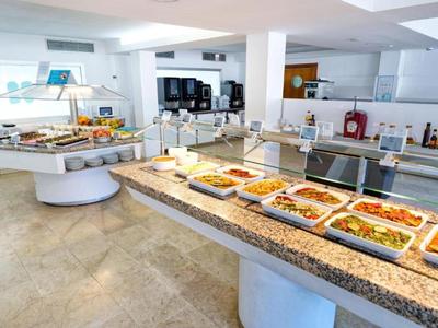 Buffet mit diversisierten warmen Speisen in einer modernen Hotelküche mit heller Einrichtung.