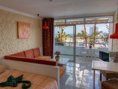 Camera d'hotel accogliente con divano, letto e balcone con vista sul mare.