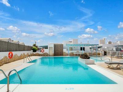 Modern outdoor pool with lounge chairs and clear blue water under a blue sky.