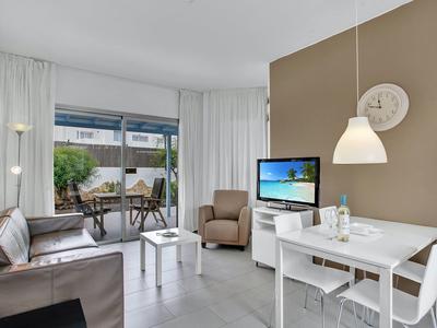 Modern living area with seating, dining table, and terrace overlooking greenery.