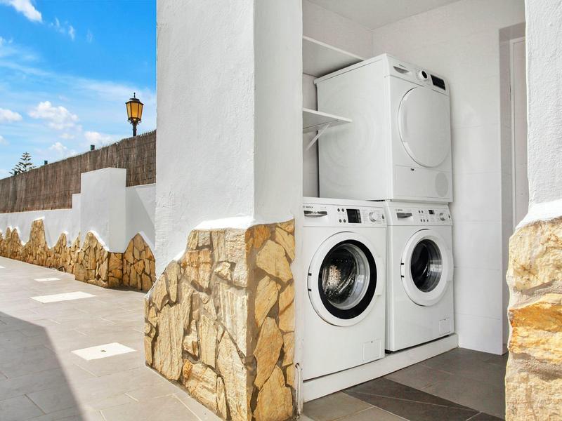 Washer and dryer in an open white laundry closet outdoors next to a walkway.