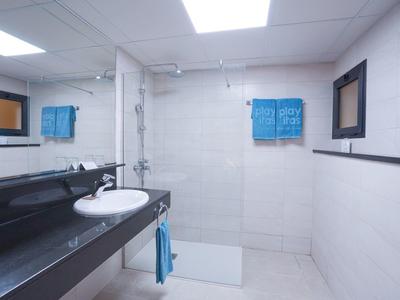 Bagno moderno con pareti piastrellate bianche, grande specchio e piano lavabo nero.