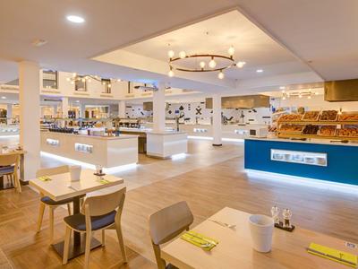 Modern, bright hotel bar with seating areas and a central counter in an open space.