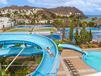Slide in a resort pool area with views of mountains and tennis courts