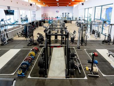 Modern gym with extensive strength and training equipment in a bright space.