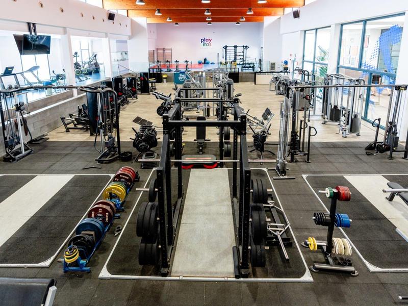 Grote moderne fitnessruimte met halters, gewichthefapparatuur en grote ramen