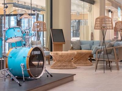 Hell eingerichteter Lounge-Bereich mit blauer Schlagzeug-Installation und moderner Sitzgruppe.