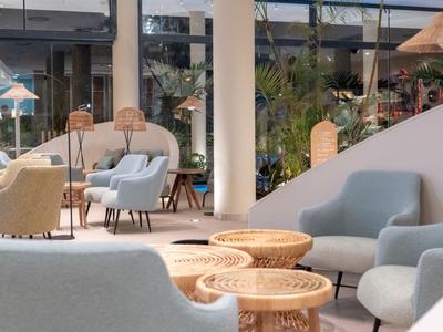 Moderne Hotellounge mit blauen Sesseln, Rattan-Tischen und dekorativem Innenbereich.