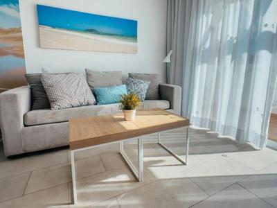 Área de estar moderna en habitación de hotel con sofá, mesa de café y ventana grande con vista a la terraza.