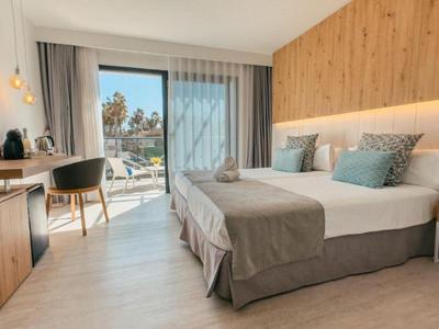 Habitación de hotel moderna con cama doble, escritorio y balcón con vista al mar.
