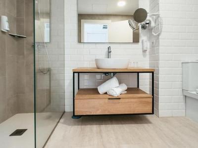 Baño moderno con ducha, lavabo, espejo y aseo en un hotel.