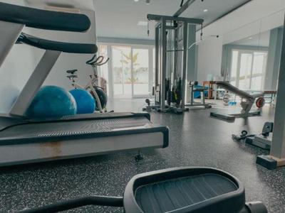 Gimnasio moderno de hotel con cinta de correr, máquinas de entrenamiento y pelotas de ejercicio.