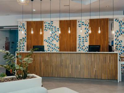 Área de recepción moderna en hotel con detalles de madera y plantas verdes.
