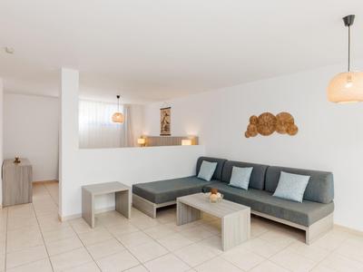 Sala de hotel luminosa con sofá gris, cojines y detalles de madera moderna.