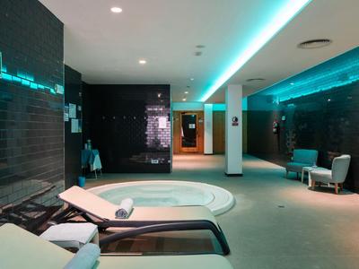Área de bienestar moderna con sauna, tumbonas e iluminación tenue.