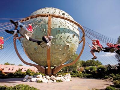 Karussell mit Mond-Design und schwingenden Sitzen in einem Freizeitpark bei klarem Himmel