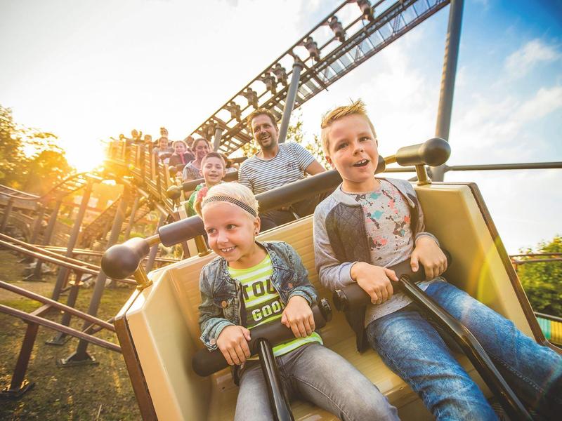 Zwei Jungen freuen sich in einer Achterbahn bei sonnigem Wetter mit blauem Himmel.
