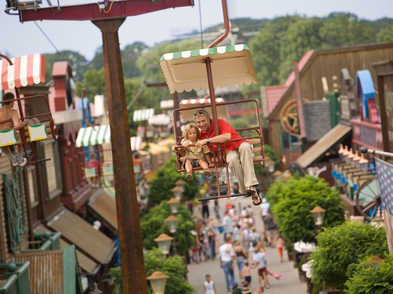 Belebte Straße mit bunten Häusern, vielen Menschen und einer Seilbahn im Vordergrund.