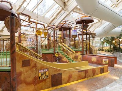 Innenbereich eines Hotels mit einem sonnendurchfluteten Spielplatz und Rutschen im Kinderbereich.