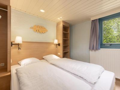 Cozy double room with white beds, wooden furniture, and window overlooking greenery.